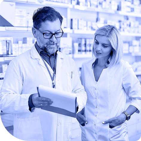 Male and female pharmacist standing together looking at notepad