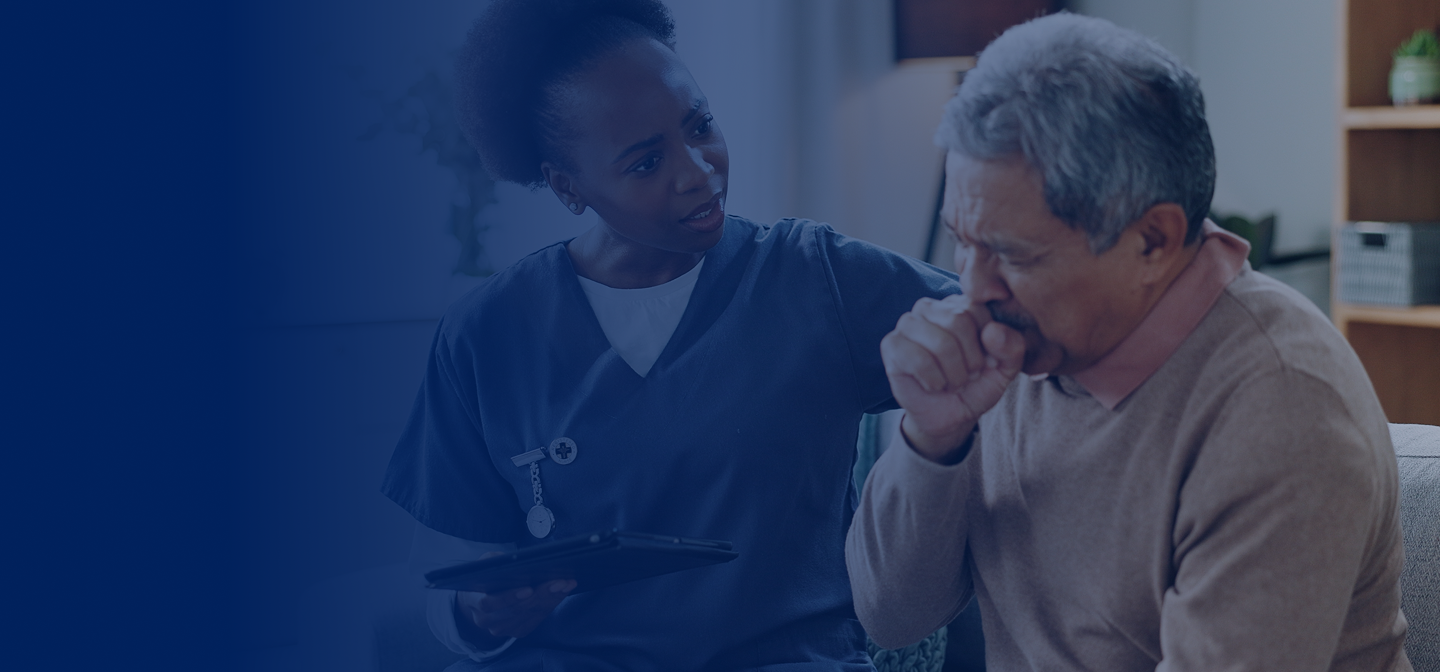 Female nurse sitting next to older man who is coughing