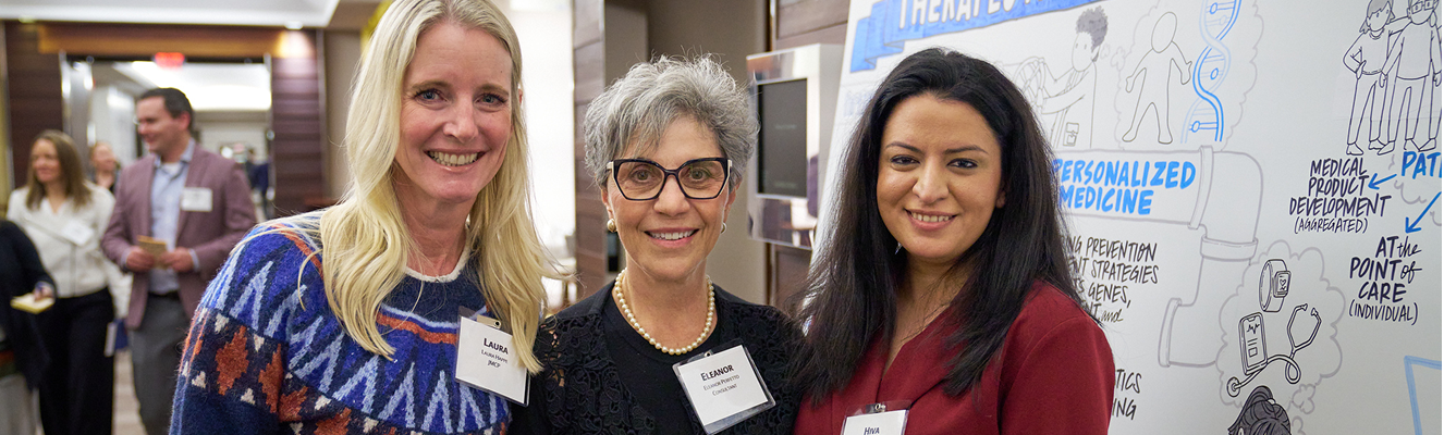 Three women at a conference, standing smiling for camera