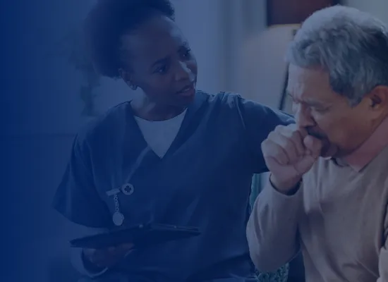 Female nurse sitting next to older man who is coughing